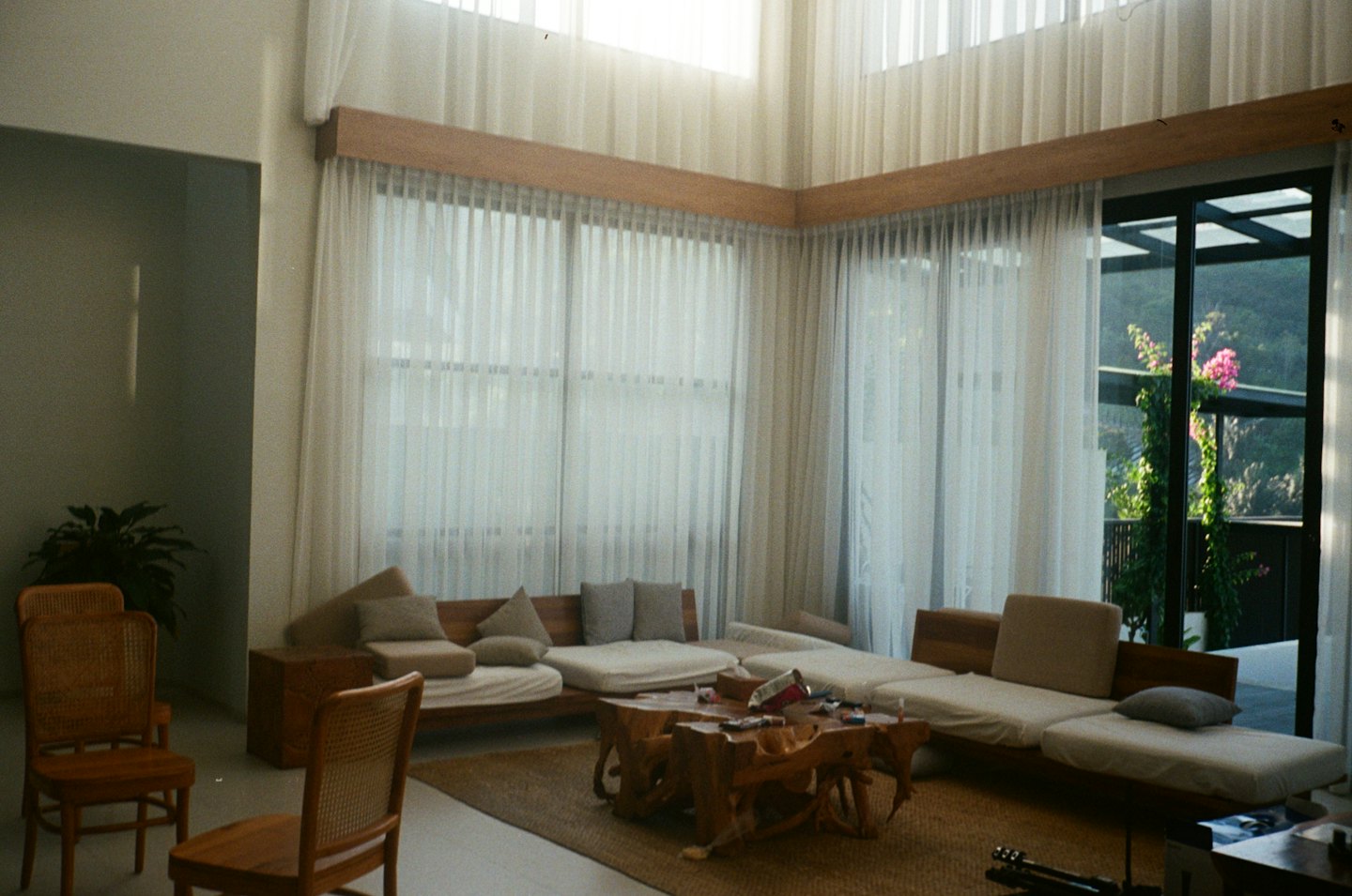 Sala de estar moderna con muebles y suelo de madera y ventanas de suelo a techo.