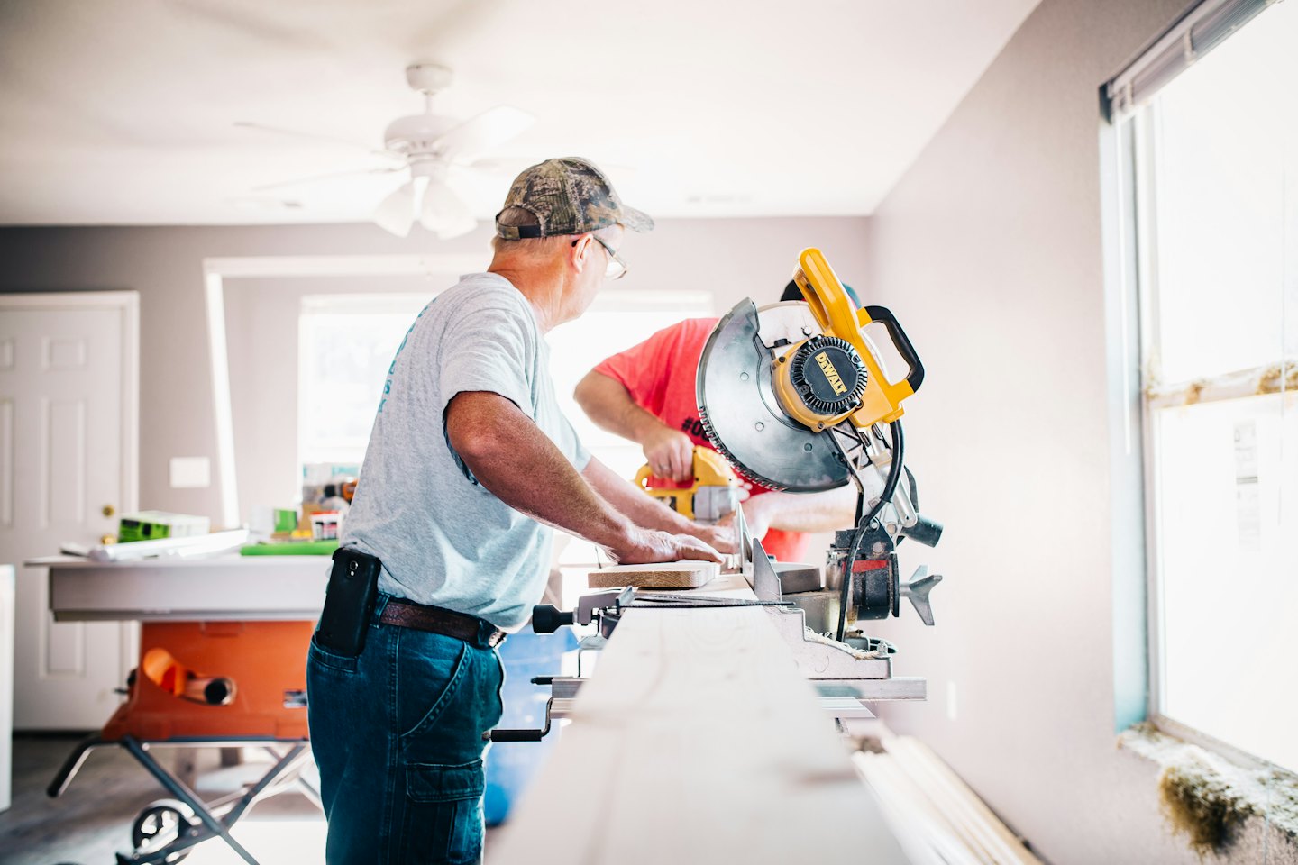 Dos hombres trabajando con sierras en madera en una habitación en renovación.