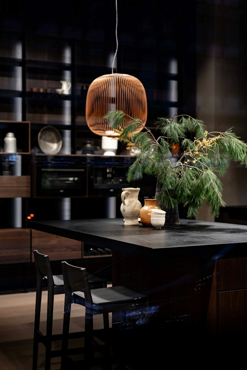Isla de cocina moderna de madera oscura con ramas de pino y bayas amarillas.