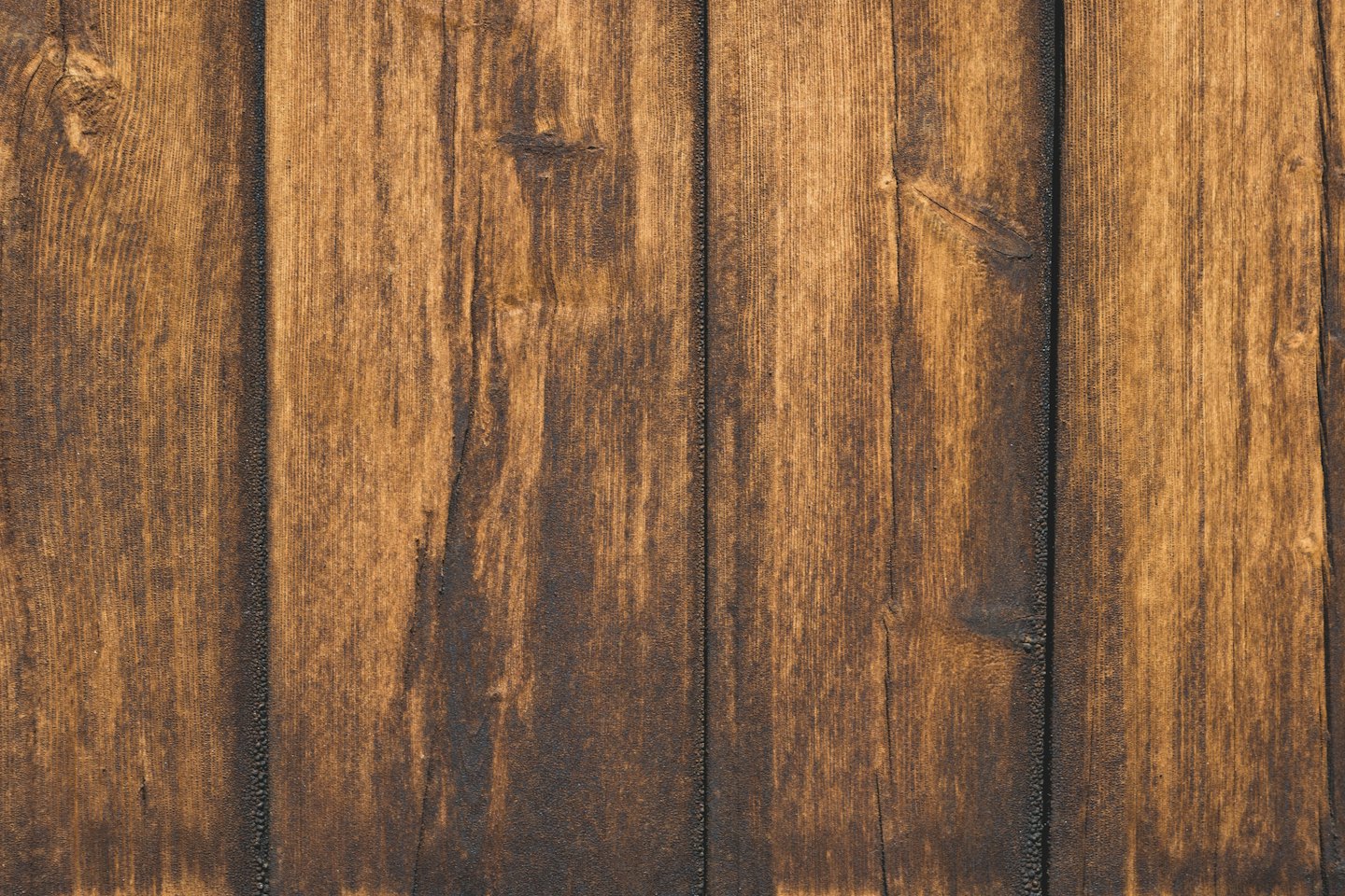 Tablones de madera de color marrón oscuro con vetas y nudos visibles.