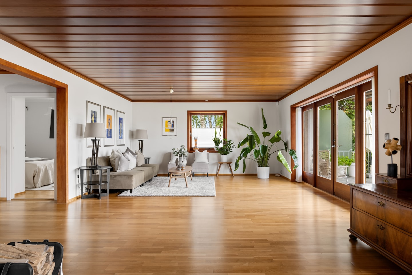 Sala de estar luminosa con suelos de madera y plantas verdes.