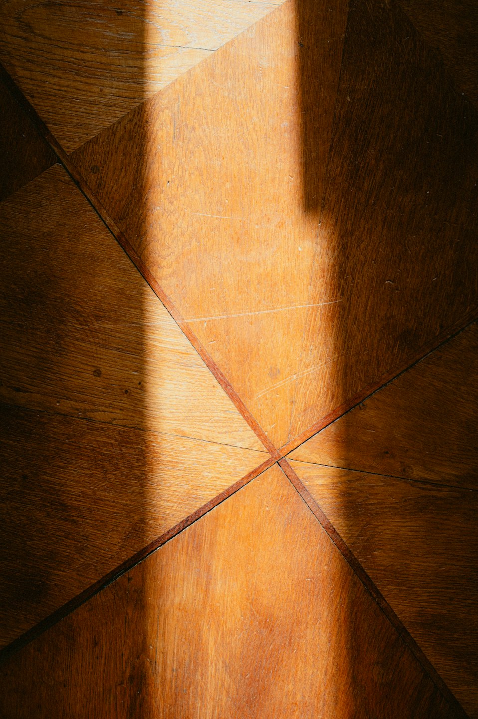 Suelo de parqué de madera geométrica con una sombra diagonal marcada.